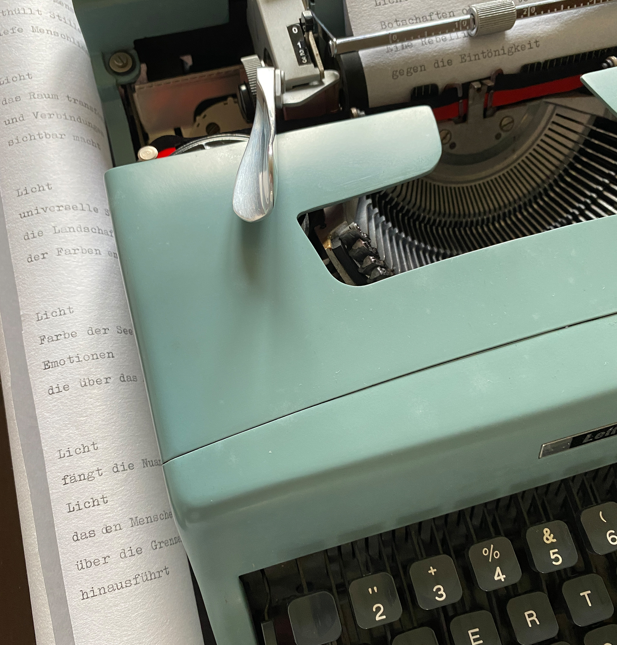 Schreibmaschine mit eingespanntem Papier und Textrolle, die neben diese liegt